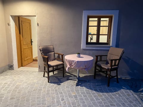 Innenhof am Abend mit beleuchteten Türen und Bistrotisch